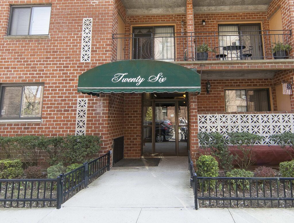 Entrance to 26 Oliver Street under the green Twenty Six awning, with planted beds on either side of the walkway.